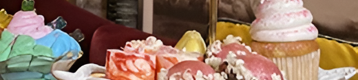 A tiered dessert platter with colorful cupcakes, macarons, candy toppers, and a rainbow flag; sweet treats overflow the plates, deliciously displayed.