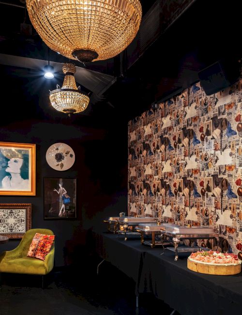 A cozy, art-filled dining area with collage-wall decor, warm lighting, and a buffet of desserts and snacks.