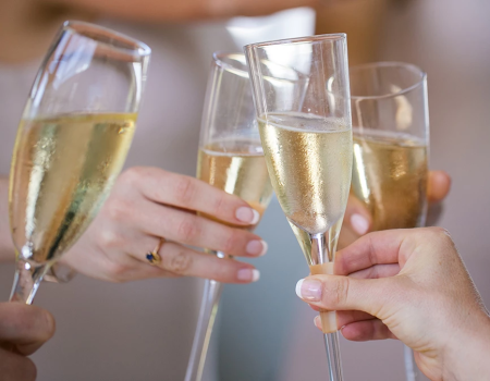 People toasting with flutes of champagne in a celebration, clinking glasses.